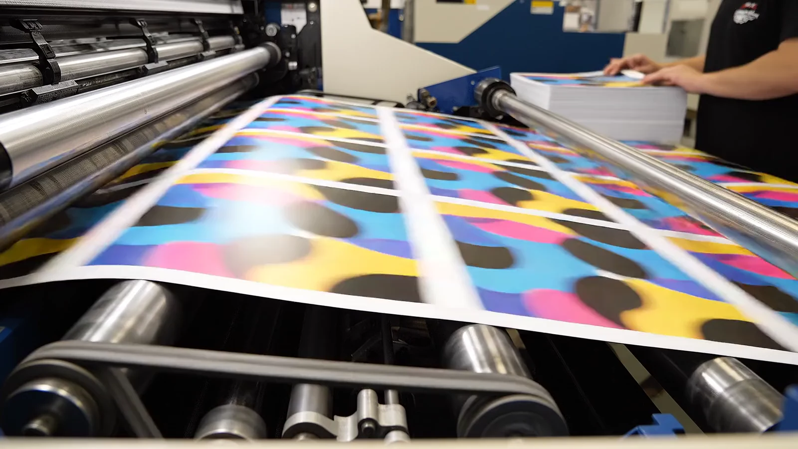 Colorful printed sheets moving over the rollers of a commercial printing line